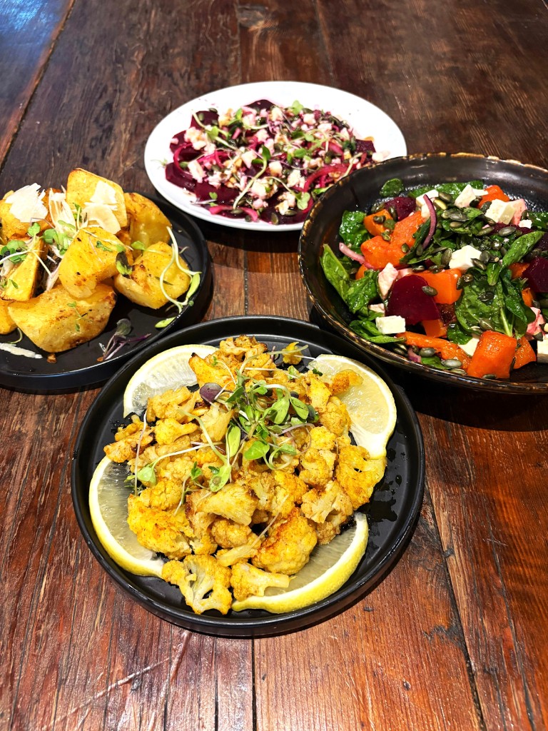 Four vegetarian plates on a wooden table at Farina